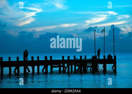 Paare gehen auf einem Pier bei Sonnenuntergang, Cozumel, Mexiko. Stockfoto