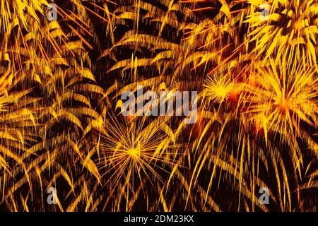 Feiertagsfeuerwerk. Bunte goldene Funken, glühender Regen von Kometen und funkelnde Sterne am schwarzen Himmel. Abstrakter festlicher Hintergrund Stockfoto