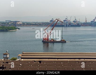 Ein Schwimmkran segelt langsam in den Alten Hafen von Rio de Janeiro bei Porto Atlantico, über die alten Lagerhäuser, die abgerissen werden. Stockfoto