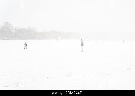 12.13.2020 Moskau, Russland. Menschen gehen Eislaufen auf einem gefrorenen See im Schnee. Menschen sind nicht sichtbar wegen des Schneesturms. Winteraktivität Stockfoto