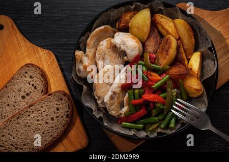 Gebackenes Huhn, Kartoffeln und Gemüse in einer gusseisernen Pfanne. Stockfoto