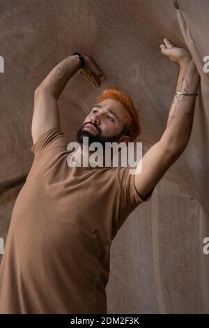 Porträt eines jungen Mannes mit orangenen Haaren, die sich nach hinten lehnen Eine Steinmauer Stockfoto