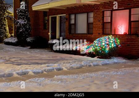Abends beleuchtete Haus und Straße in der verschneiten Wohngegend Und Parkplatz Stockfoto