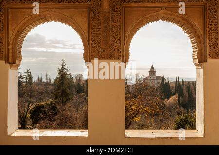 Detail von zwei Fenstern mit geometrischen Elementen der islamischen Kunst, durch die eine Landschaft gesehen werden kann dekoriert. Alhambra in Granada, Spanien. Stockfoto