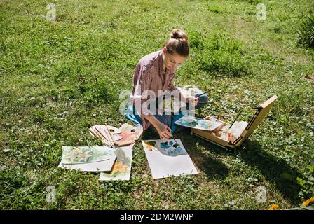 Künstlerin zeichnet Blumen mit Ölfarben im Freien, en plein Air Maler, selektiver Fokus Stockfoto