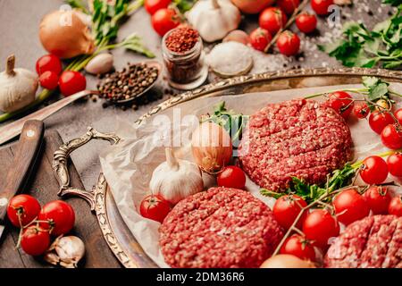 Hackfleisch-Hackfleisch-Hacksteaks aus Hackfleisch Vorbereitet für auf einer Platte.Hamburger Fleisch gewürzt und bereit für Ein Grill.Gewürze und Co Stockfoto