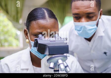 Ein junger afrikanischer Wissenschaftler schaut durch ein Mikroskop im Labor Stockfoto