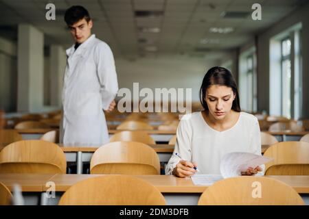 Studentin, die eine Prüfung in einem leeren Amphitheater abgelegt hat. Gestresster Student, der in-class Test. Betroffene Frau mit Bildungsbewertung.Supervisor Stockfoto