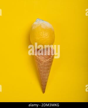 Verfaultes, verdorbenes Zitronen- und Waffelhorn auf gelbem Hintergrund. Kreatives Layout, Draufsicht, minimalistischer Trend, flaches Lay Stockfoto