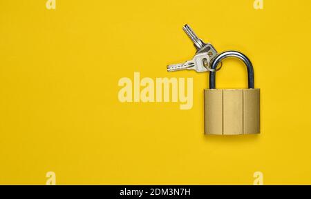 Golden closed lock with keys on a yellow background. Copy space. Top View Stockfoto