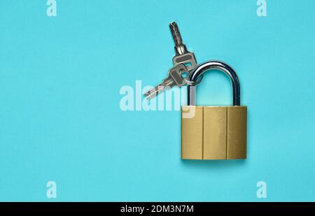 Golden closed lock with keys on a blue background. Copy space. Top View Stockfoto