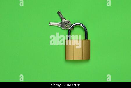 Golden closed lock with keys on a green background. Copy space. Top View Stockfoto