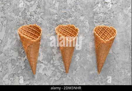 Three empty waffle horns on a concrete background. Top view, creative background, minimalist trend Stockfoto