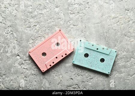 Blaue und rosa Pastell-Audiokassetten auf grauem Beton-Hintergrund. Draufsicht, Kopierbereich Stockfoto
