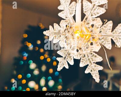 Gemütliche Atmosphäre für Weihnachten mit Weihnachtsbeleuchtung im Vordergrund und Bokeh-Effekt auf Weihnachtsbaum Stockfoto