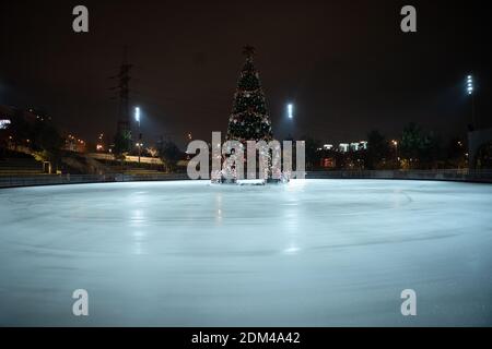 Weihnachten Eisbahn mit verzierten Tannenbaum leer während Quarantäne Pandemie Coronavirus und covid 2019 am Abend in der Ukraine, Kiew. Eisbahn Stockfoto