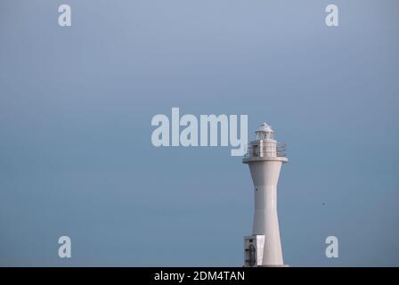 Weißer Leuchtturm, der unter dem hellblauen Himmel aufragt Stockfoto