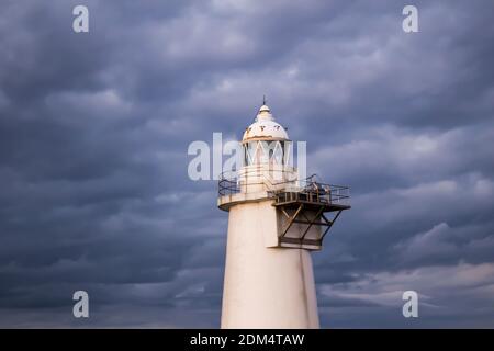 Weißer Leuchtturm, der bei bewölktem Wetter aufragt Stockfoto