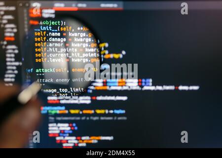 Programmcode auf dem Computerdisplay in der Lupe. Nahaufnahme. Hochwertige Fotos Stockfoto