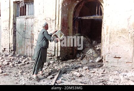 Ein afghanischer Ladenbesitzer wirft Eimer Wasser auf seinen Laden, nachdem er von Artilleriebeschossen wurde, die von Truppen abgefeuert wurden, die dem Kriegsherrn Gulbuddin Hekmatyar am 27. April 1992 in Kabul, Afghanistan, treu sind. Nach dem Zusammenbruch der Demokratischen Republik Afghanistan rivalisierende Fraktion der Mudschaheddin begann einen Kampf um die Stadt. Quelle: Planetpix/Alamy Live News Stockfoto
