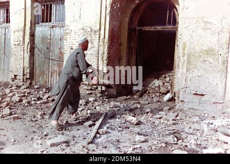 Ein afghanischer Ladenbesitzer wirft Eimer Wasser auf seinen Laden, nachdem er von Artilleriebeschossen wurde, die von Truppen abgefeuert wurden, die dem Kriegsherrn Gulbuddin Hekmatyar am 27. April 1992 in Kabul, Afghanistan, treu sind. Nach dem Zusammenbruch der Demokratischen Republik Afghanistan rivalisierende Fraktion der Mudschaheddin begann einen Kampf um die Stadt. Quelle: Planetpix/Alamy Live News Stockfoto