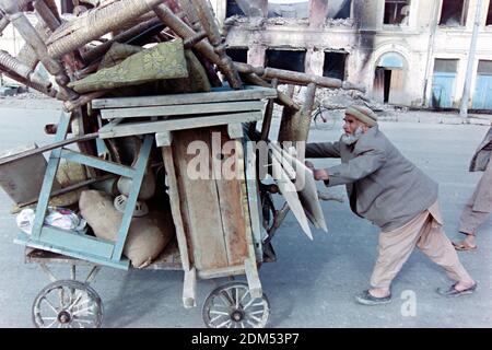 Ein afghanischer Ladenbesitzer schiebt einen Wagen mit seinen Habseligkeiten, nachdem sein Geschäft von Raketen getroffen wurde, die von Truppen des Kriegsfürsten Gulbuddin Hekmatyar am 27. April 1992 in Kabul, Afghanistan, abgefeuert wurden. Nach dem Zusammenbruch der Demokratischen Republik Afghanistan rivalisierende Fraktion der Mudschaheddin begann einen Kampf um die Stadt. Quelle: Planetpix/Alamy Live News Stockfoto