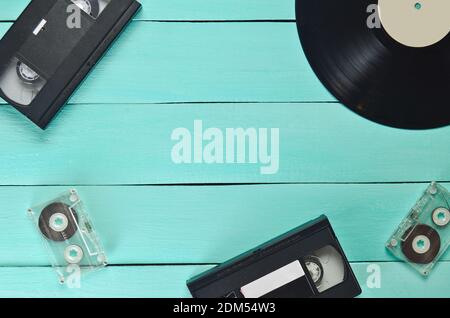 Schallplatte, Videokassette, Audiokassette auf blauem Holzhintergrund. Draufsicht. Retro-Medientechnik, Kopierbereich Stockfoto