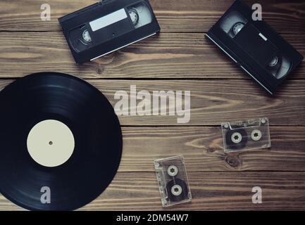 Schallplatte, Videokassette, Audiokassette auf einem Holzhintergrund. Draufsicht. Retro-Medientechnik, Kopierbereich Stockfoto