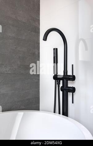 Neuer schwarzer Wasserhahn und Duschkopf gegen saubere geflieste weiße und graue Wand des Badezimmers in der modernen Wohnung. Stockfoto