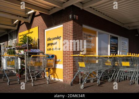 Gelbe Einkaufswagen der niederländischen Supermarktkette Jumbo geparkt Vor dem Laden mit Werbetafeln Stockfoto