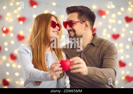 Das junge Ehepaar blickt zärtlich in die Augen und hält ein kleines rotes Herz. Stockfoto