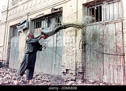 Ein afghanischer Ladenbesitzer wirft Eimer Wasser auf seinen Laden, nachdem er von Artilleriebeschossen wurde, die von Truppen abgefeuert wurden, die dem Kriegsherrn Gulbuddin Hekmatyar am 27. April 1992 in Kabul, Afghanistan, treu sind. Nach dem Zusammenbruch der Demokratischen Republik Afghanistan rivalisierende Fraktion der Mudschaheddin begann einen Kampf um die Stadt. Quelle: Planetpix/Alamy Live News Stockfoto