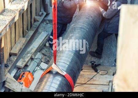 Professioneller Schweißer, der Wasser- oder Gasstahlleitung in Schutzgraben und Maske an Baustellengrube schweißt. City Underground verwendet Erneuerung Stockfoto