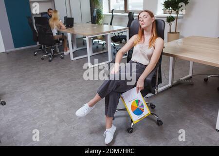 Junge müde Geschäftsfrau schlafen in ihrem Stuhl auf freiem Raum Büro Stockfoto