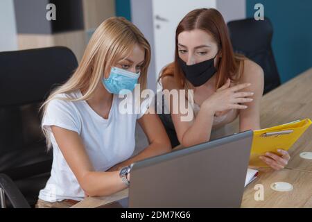 Weibliche Kollegen in schützenden Gesichtsmasken im Büro Stockfoto