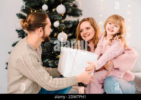 Familie, die ihrer Tochter weihnachtsgeschenke schenkt Stockfoto