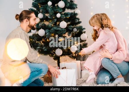 Glückliche Familie gibt ihrer Tochter Weihnachtsgeschenke. Kleines Mädchen freut sich geschenkbox Stockfoto