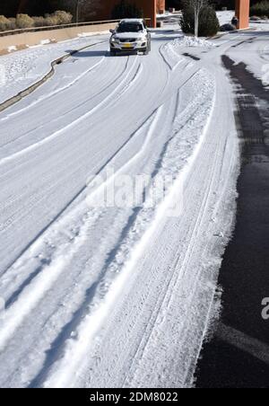 Eine Autofahrerin fährt ihr Auto auf einer schneebedeckten Straße in Sasnta Fe, New Mexico. Stockfoto