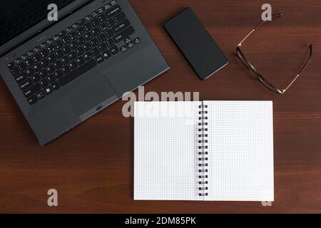 Top view of office stuff with laptop, smartphone, notepad, and glasses Stock Photo