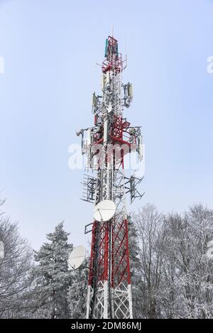 Winteransicht des rot-weißen Kommunikationsturms mit TV Und mit Frost überzogene Antennen Stockfoto