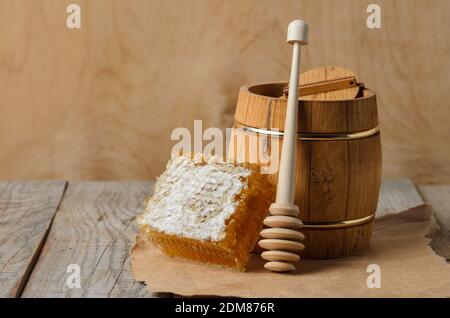 Honig in Honigwabe mit einem Holzkrug und Löffel auf einem rauen Holzhintergrund. Selektiver Fokus. Stockfoto