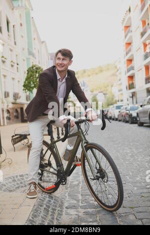 In voller Länge Schuss eines fröhlichen reifen Geschäftsmann überqueren die Straße auf seinem Fahrrad Stockfoto