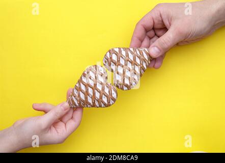 Männliche und weibliche Hände halten zwei Lebkuchen in der Form Der Herzen Stockfoto