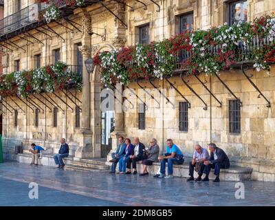 Die Menschen entspannen sich auf den Steinbänken vor dem Rathaus auf dem Hauptplatz (Plaza Mayor) - Leon, Kastilien und Leon, Spanien Stockfoto