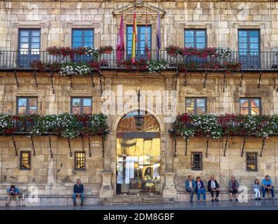 Die Menschen entspannen sich auf den Steinbänken vor dem Rathaus auf dem Hauptplatz (Plaza Mayor) - Leon, Kastilien und Leon, Spanien Stockfoto