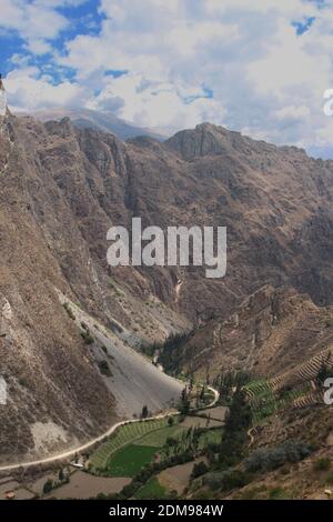 Bauernterrassen an der Seite des Patacancha Mountain in Die Anden und Ackerland und eine Schotterstraße hinein Das Tal in der Region Cusco von per Stockfoto