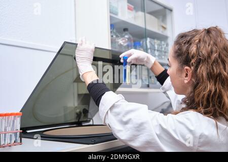 Junge Wissenschaftlerin, die in einem Labor mit einer Zentrifuge arbeitet. Laborforschungskonzept. Stockfoto