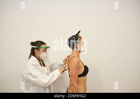 Physiotherapeut arbeitet mit dem Patienten in der Klinik. Sie tragen Masken, um die Ausbreitung des Corona-Virus zu verhindern Stockfoto