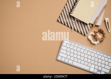 Eleganter femininer Arbeitsplatz, Schreibtisch mit Tastatur, Notizbücher aus Papier, Accessoires auf pastellbeigem Hintergrund. Flach liegend, Blick von oben. Stockfoto