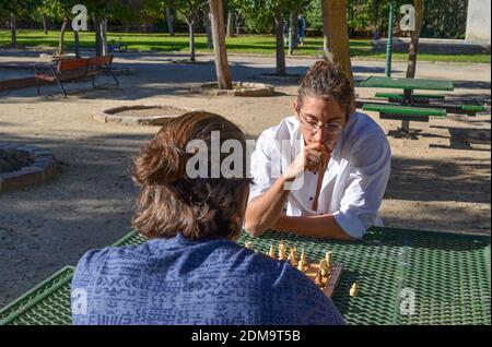 Eine Nahaufnahme von zwei Jungs spielen Schach in der park in der Nähe der Bäume auf der Bank Stockfoto